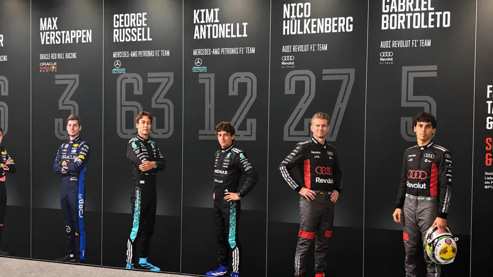 Life size prints of current Formula 1 drivers along a black wall with their race numbers