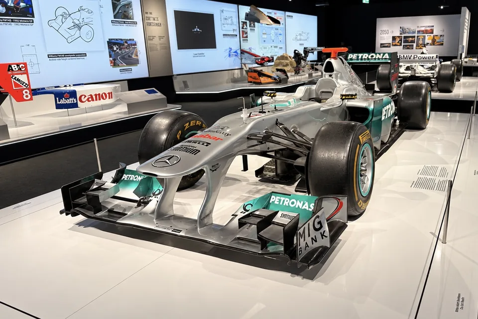 Silver and green Mercedes Formula 1 car on a white display floor