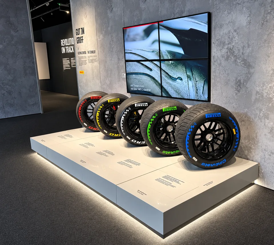 Five Pirelli Formula 1 tyre compounds lined up on a lit plinth