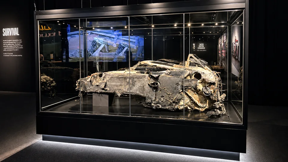 Wreckage of a Formula 1 car displayed in a lit glass case under the heading Survival