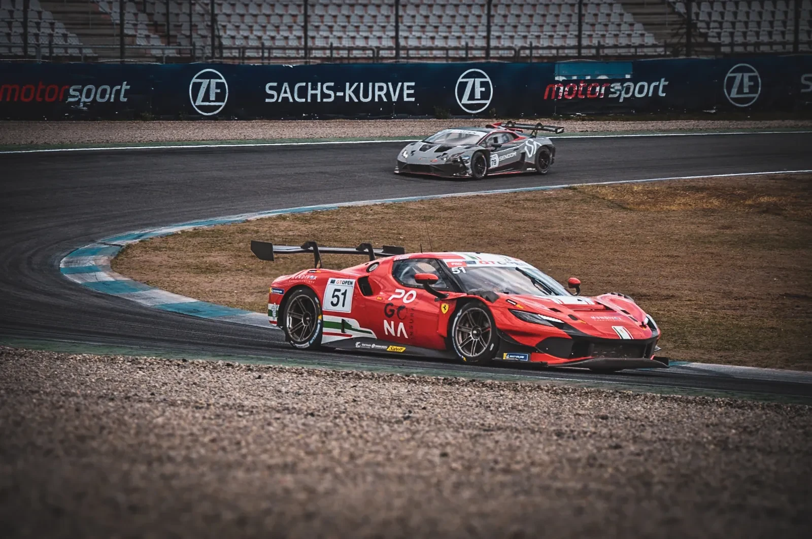Red number 51 Ferrari GT car cornering at Hockenheimring with other cars behind