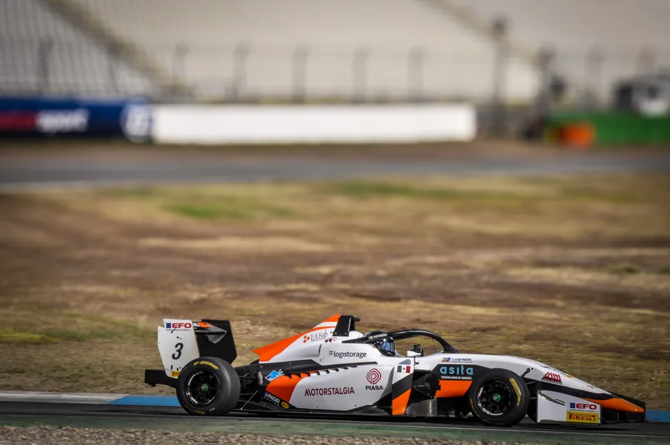 White and orange number 3 single-seater race car in profile riding the kerb