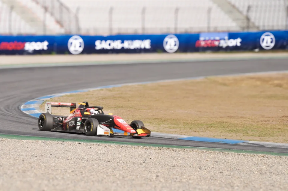 Black and red number 10 single-seater race car turning in at the Sachs-Kurve
