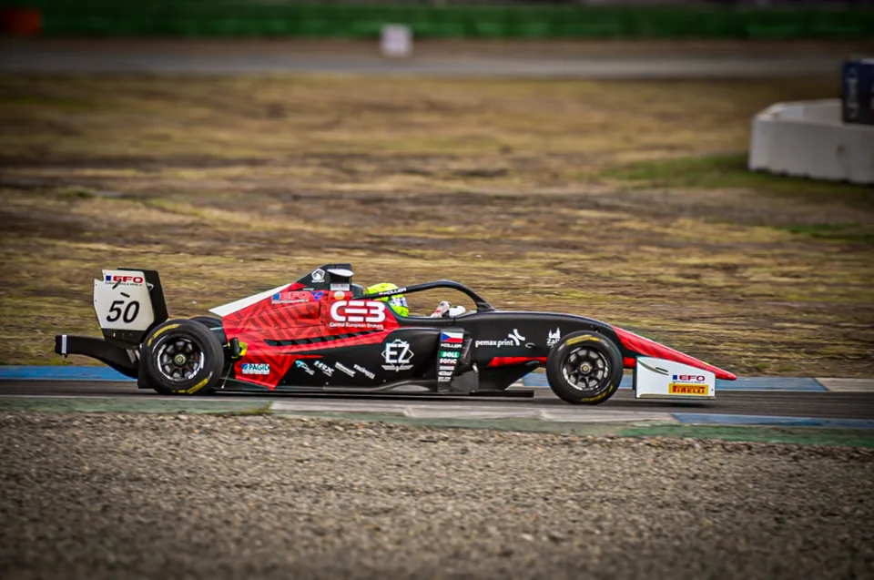 Black and red number 50 single-seater race car in profile on track