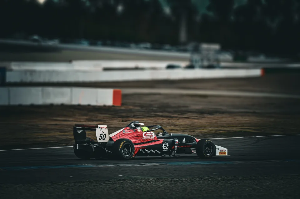 Black and red number 50 single-seater on track in flat overcast light