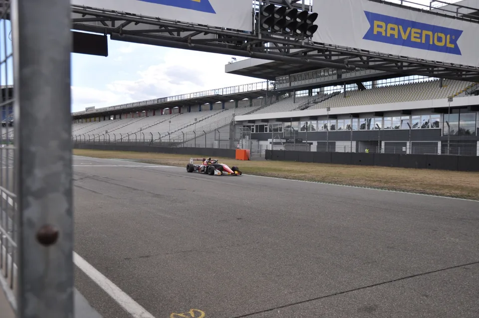 Single-seater on the main straight framed by the start line gantry and its light panels