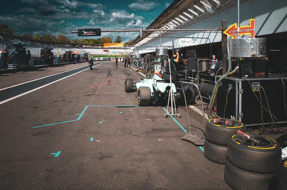 Wide view down the pit lane with a single-seater in its pit box and tyres stacked alongside
