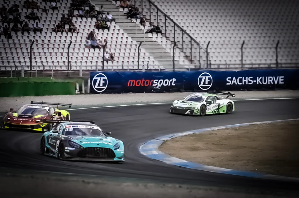 Teal number 28 Mercedes-AMG GT3 leading a Lamborghini and an Audi R8 through a corner