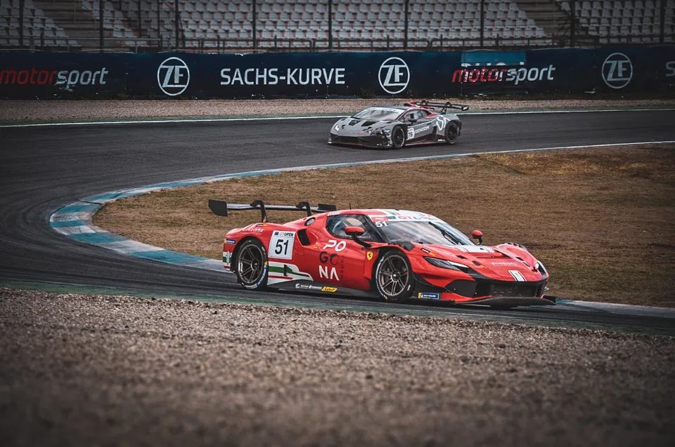 Red number 51 Ferrari 296 GT3 cornering with a grey number 79 Lamborghini behind at the Sachs-Kurve
