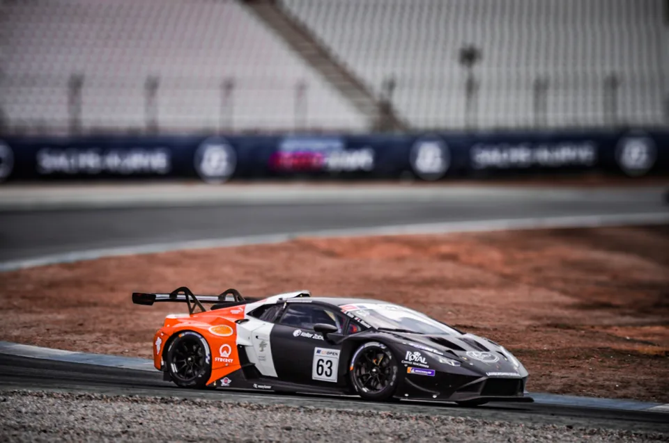 Orange, white and black number 63 Lamborghini Huracán GT3 on track in front of an empty grandstand