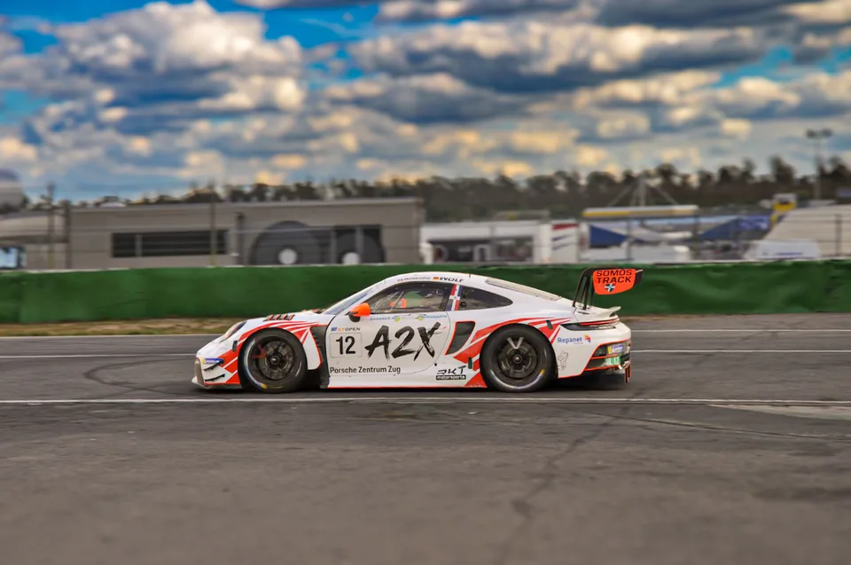 Panning shot of the number 12 Porsche 911 GT3 R at speed under a broken sky