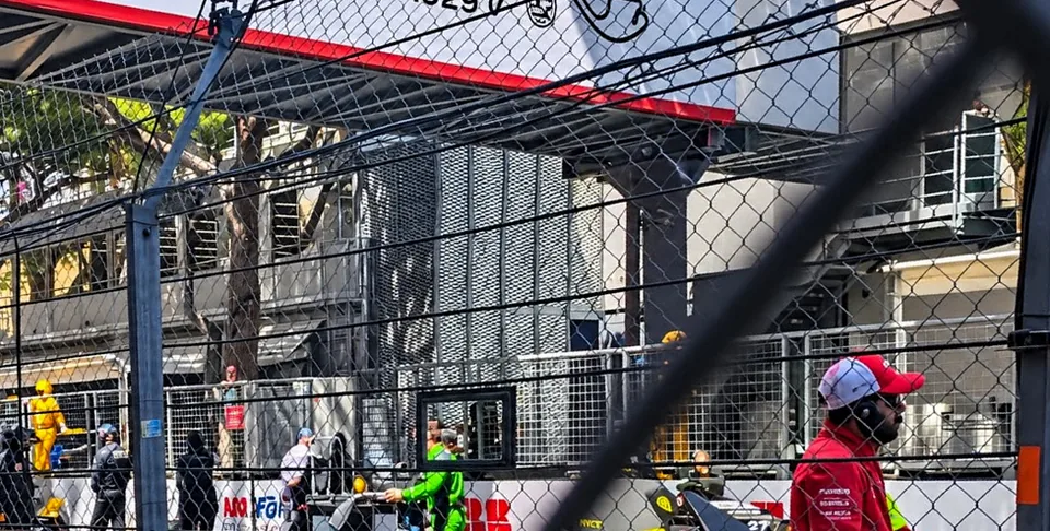 View through layered fencing towards the pit area with Monaco apartment buildings behind