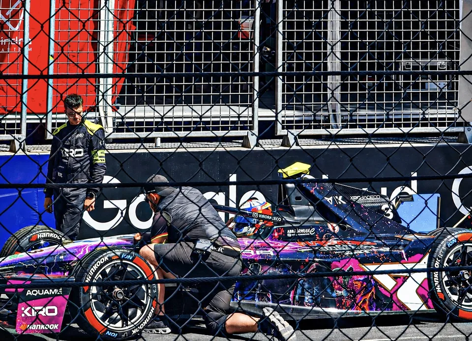 Crew working on a brightly liveried Formula E car in the Monaco pit lane