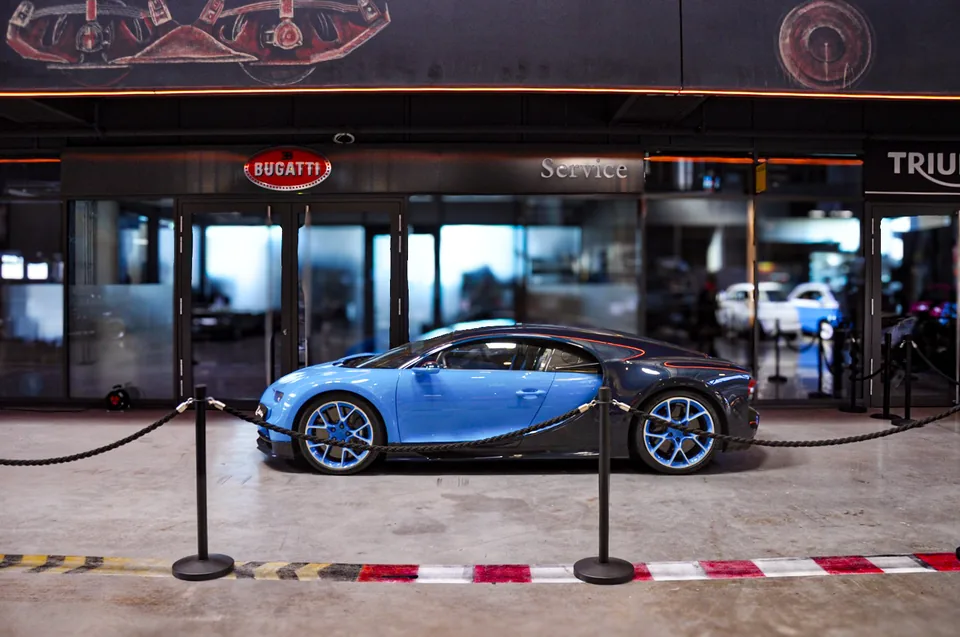 Blue and dark blue Bugatti Chiron roped off in front of a Bugatti showroom