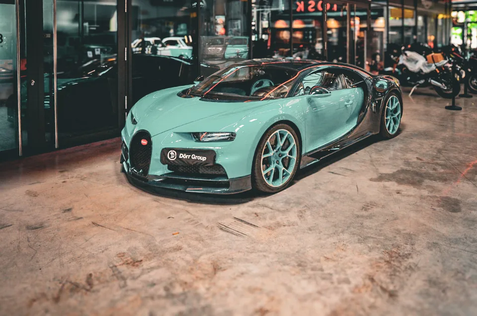 Mint green and carbon Bugatti Chiron parked on a worn concrete floor